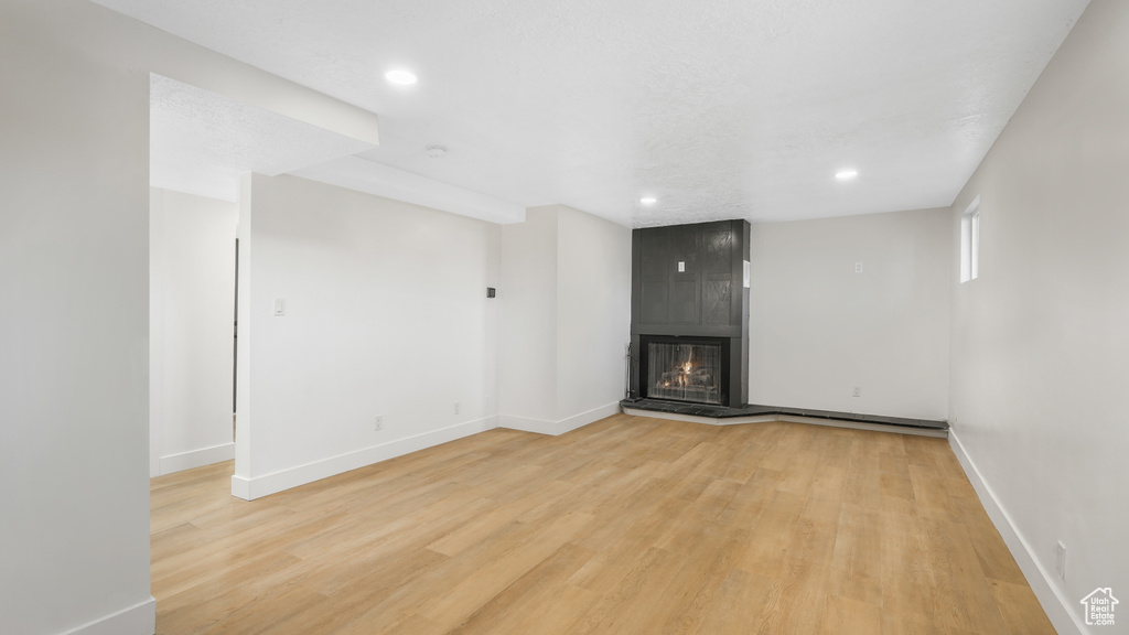 Unfurnished living room featuring light wood-type flooring and a large fireplace