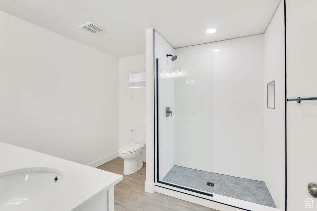 Bathroom with a shower with shower door, hardwood / wood-style floors, vanity, and toilet