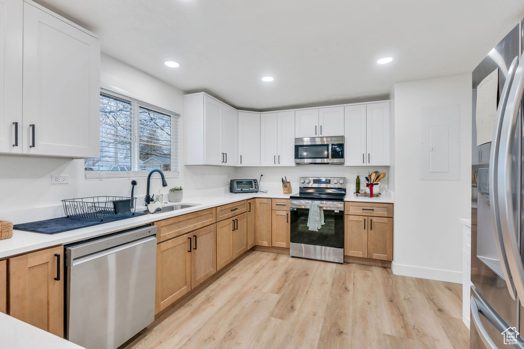 Kitchen featuring sink, appliances with stainless steel finishes, light hardwood / wood-style flooring, and white cabinets