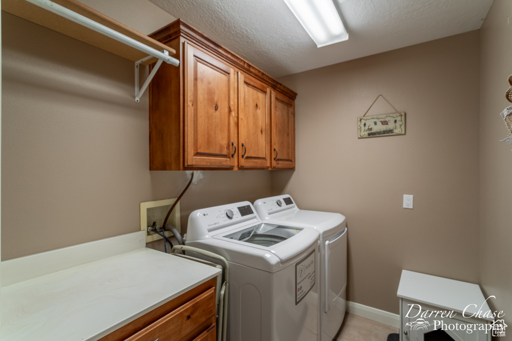 Laundry room featuring cabinets, washer hookup, washing machine and clothes dryer, and a textured ceiling