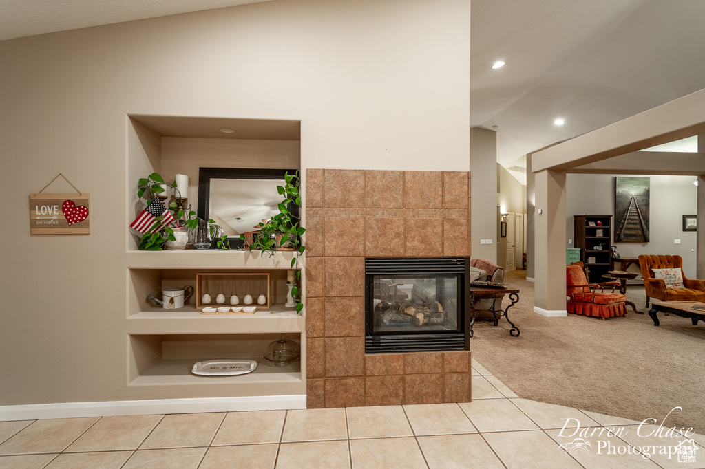 Tiled living room featuring a fireplace, lofted ceiling, and built in features