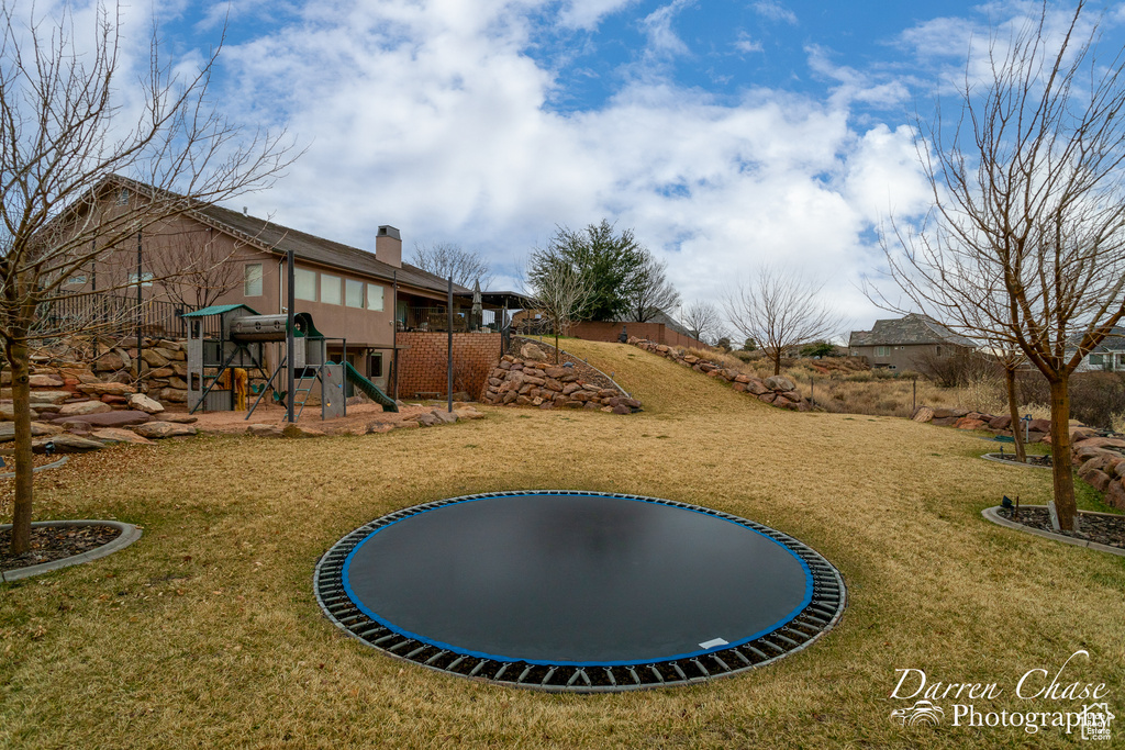View of yard with a playground and a trampoline