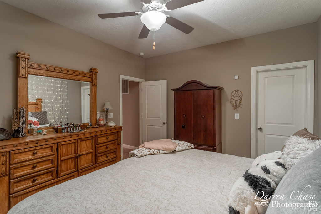 Bedroom with ceiling fan and a textured ceiling