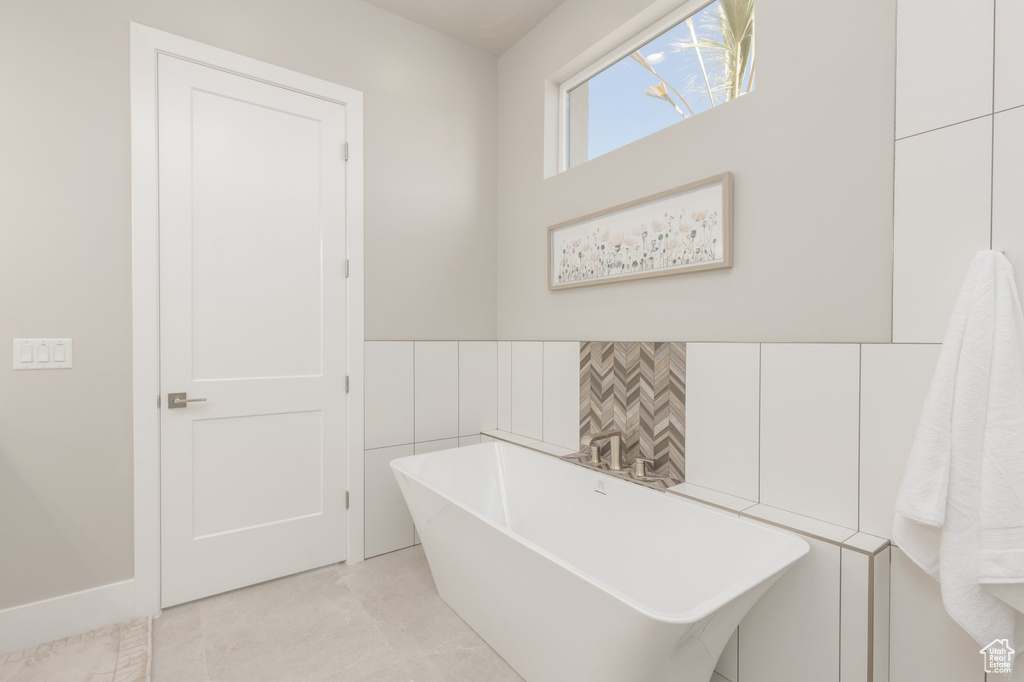 Bathroom featuring a bathtub, tile walls, and tile flooring