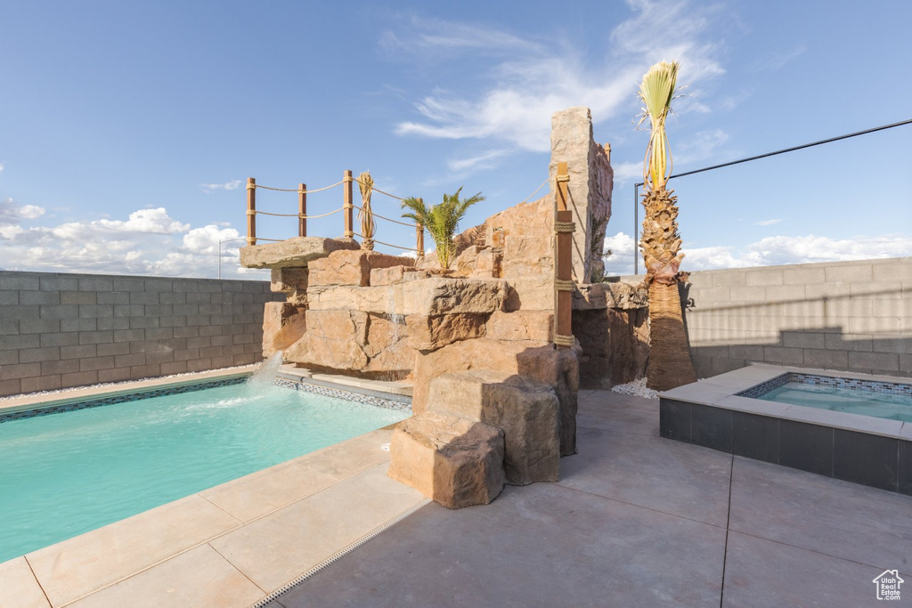 View of swimming pool with an in ground hot tub, a patio, and pool water feature