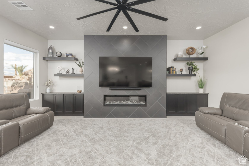 Living room with a fireplace, ceiling fan, and a textured ceiling