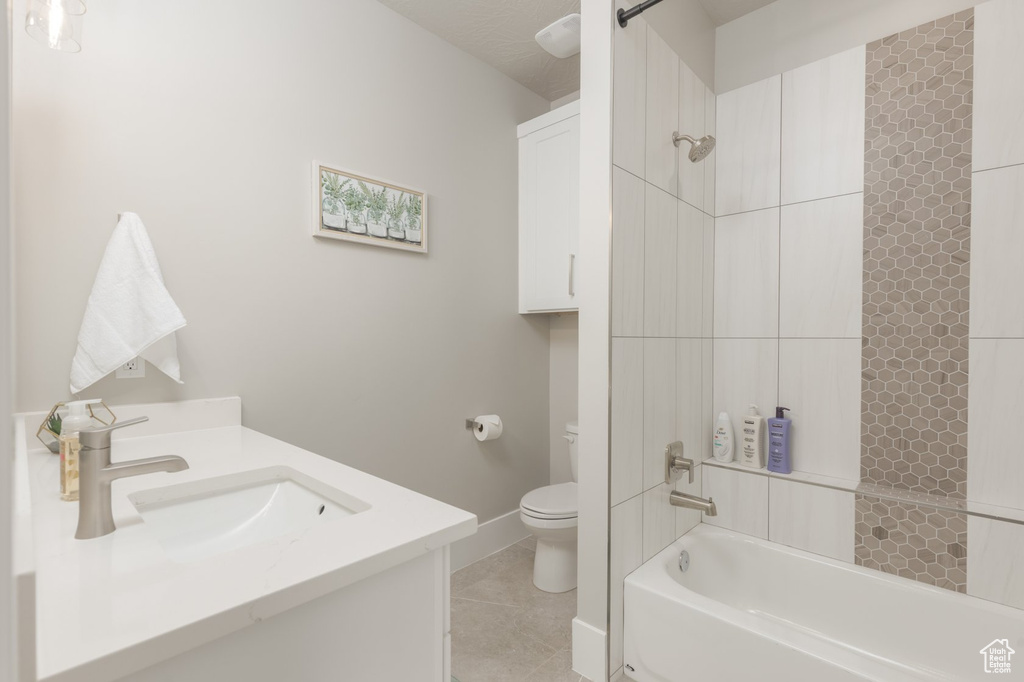 Full bathroom featuring tile floors, vanity, tiled shower / bath combo, and toilet