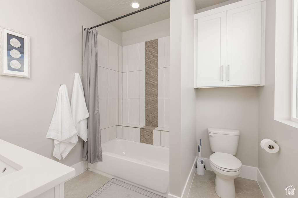 Bathroom with shower / tub combo with curtain, tile floors, and toilet