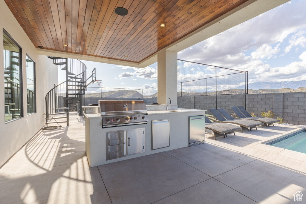 View of patio / terrace with a mountain view, an outdoor kitchen, a grill, and sink