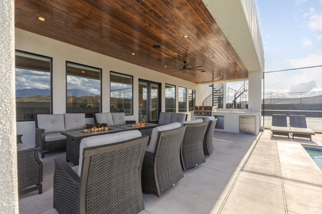 View of patio / terrace featuring exterior kitchen, ceiling fan, and an outdoor living space with a fire pit