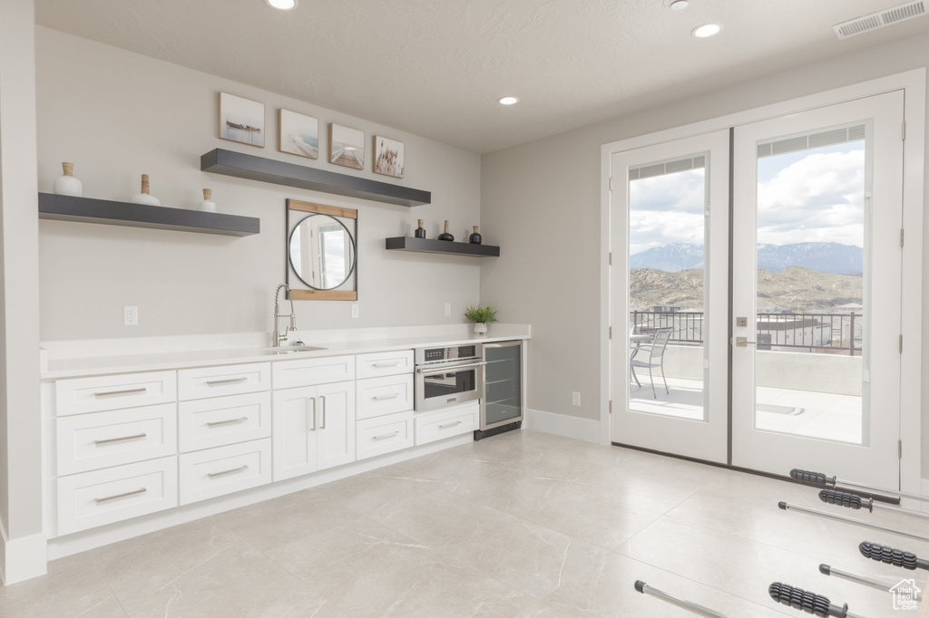 Kitchen with french doors, a mountain view, white cabinets, stainless steel oven, and light tile floors