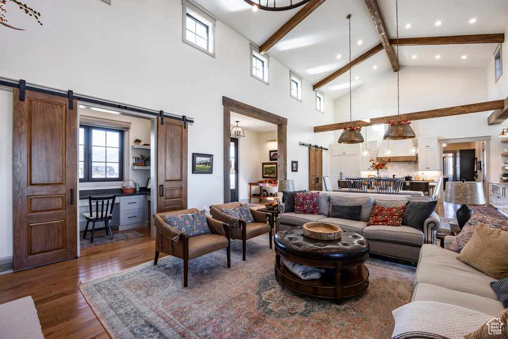 Living room with dark hardwood / wood-style floors, beam ceiling, high vaulted ceiling, and a barn door