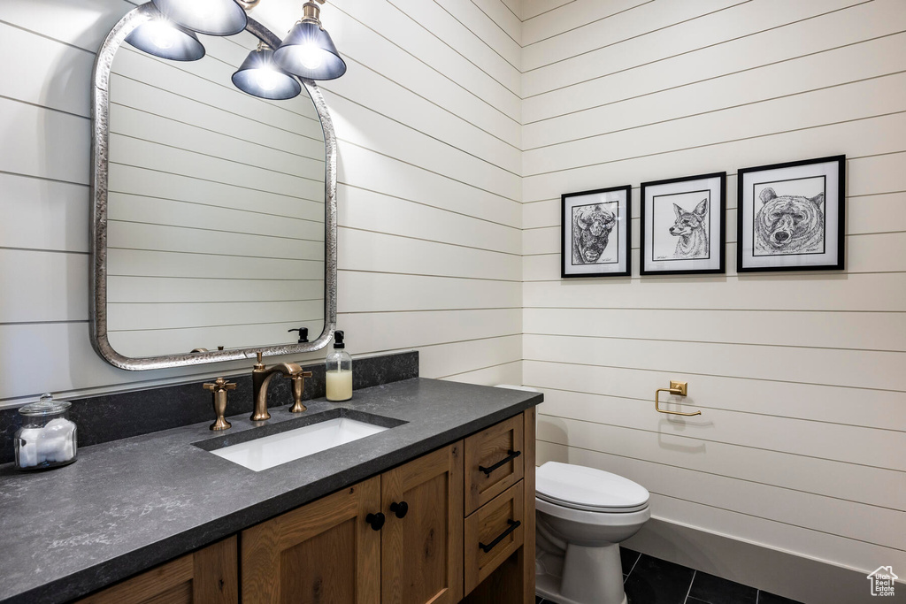 Bathroom with large vanity, wooden walls, and toilet