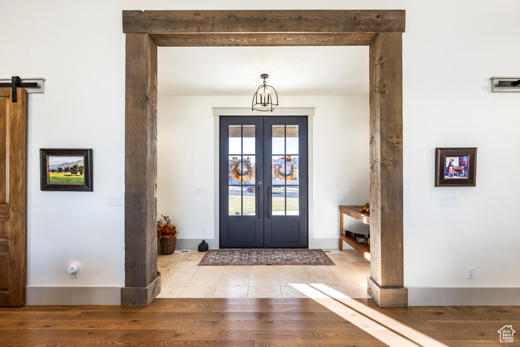 Tiled entryway featuring a barn door and french doors
