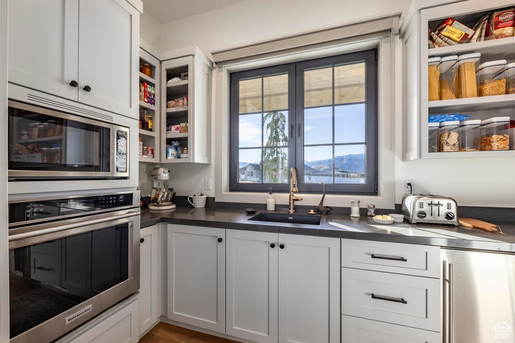 Kitchen with white cabinetry, sink, built in appliances, and a mountain view