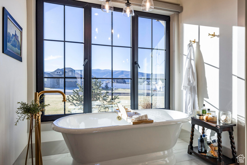 Bathroom featuring a mountain view, an inviting chandelier, tile flooring, and a bathtub