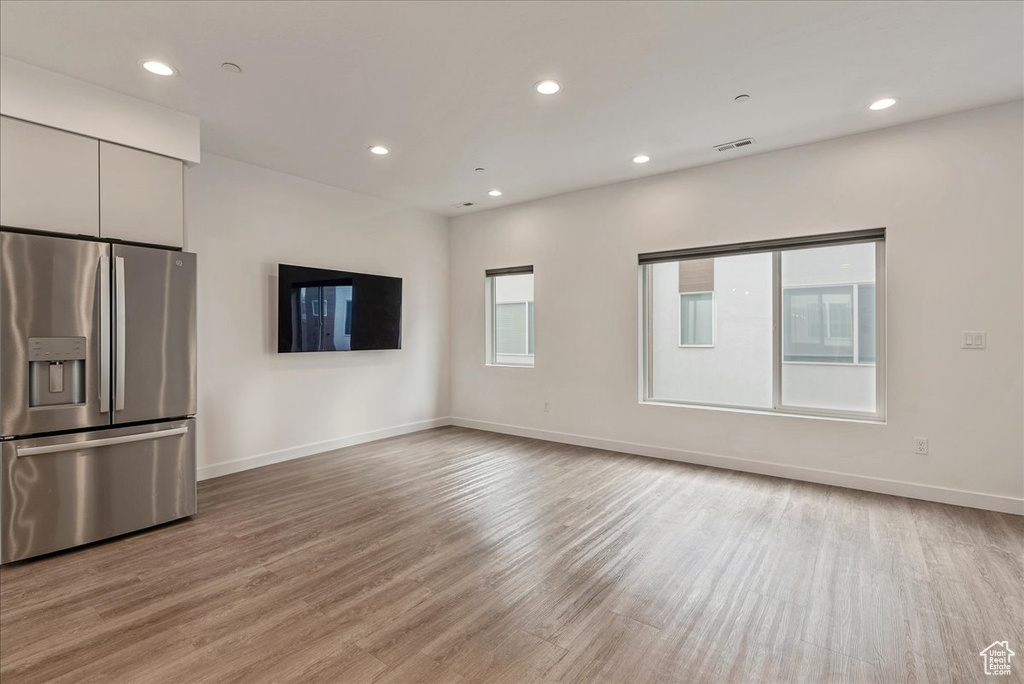 Interior space with white cabinetry, light hardwood / wood-style flooring, and stainless steel refrigerator with ice dispenser