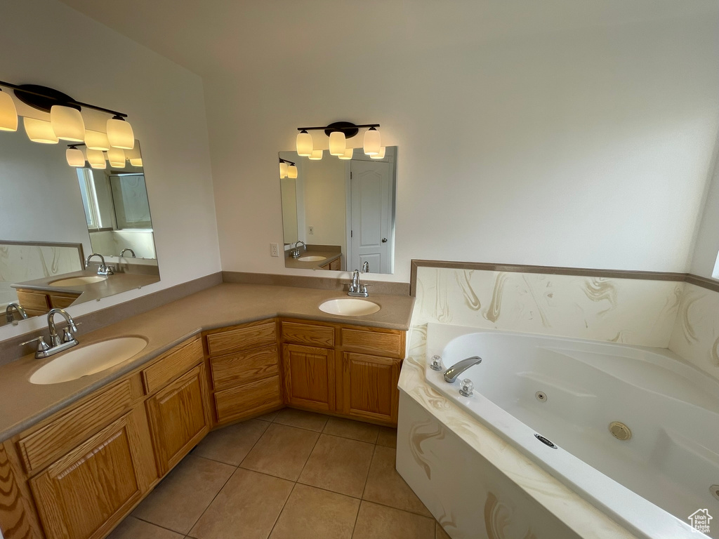 Bathroom featuring dual sinks, vanity with extensive cabinet space, and tile flooring
