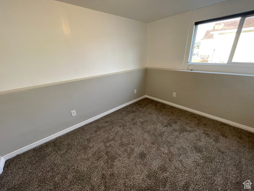 Empty room featuring dark colored carpet