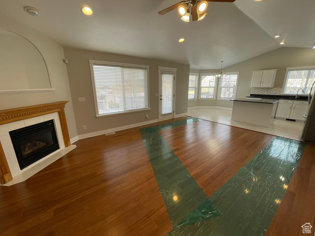 Unfurnished living room with a tiled fireplace, wood-type flooring, ceiling fan, and sink