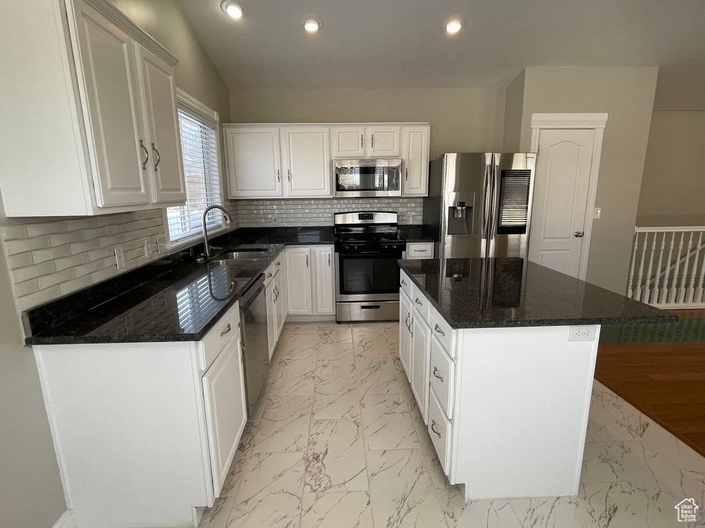 Kitchen with a kitchen island, tasteful backsplash, appliances with stainless steel finishes, sink, and light tile floors