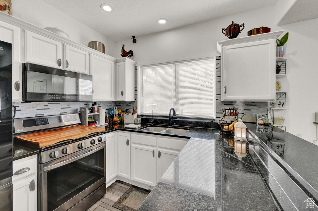 Kitchen featuring sink, tasteful backsplash, stainless steel range oven, and white cabinets
