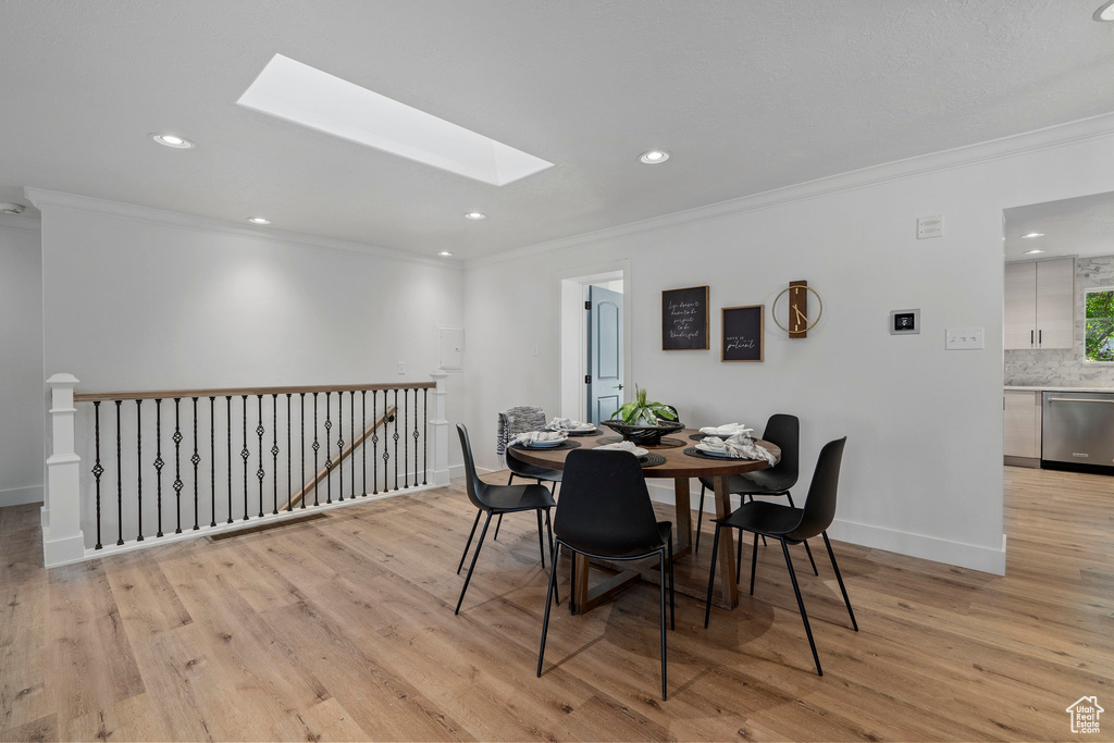 Dining space featuring light hardwood / wood-style flooring, a skylight, and ornamental molding