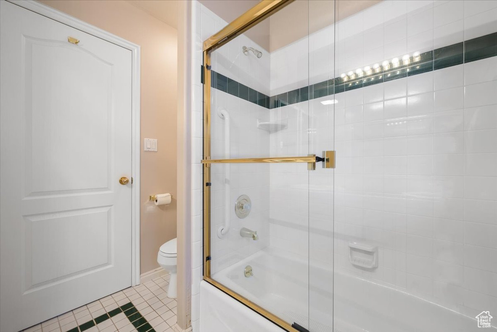 Bathroom with enclosed tub / shower combo, tile flooring, and toilet