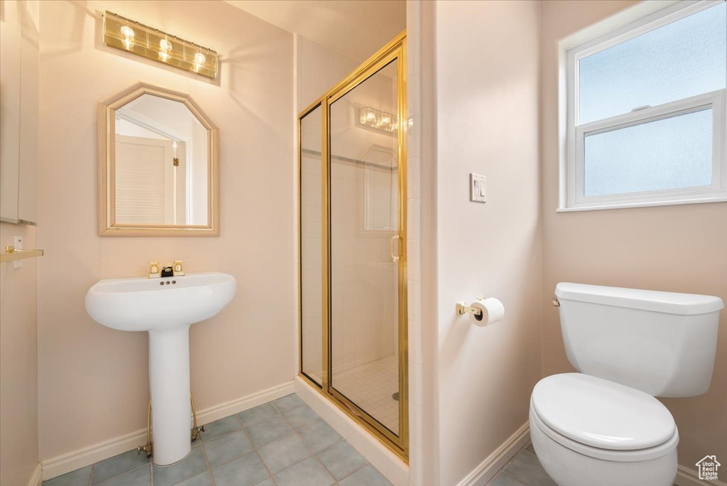 Bathroom with a shower with shower door, tile floors, and toilet