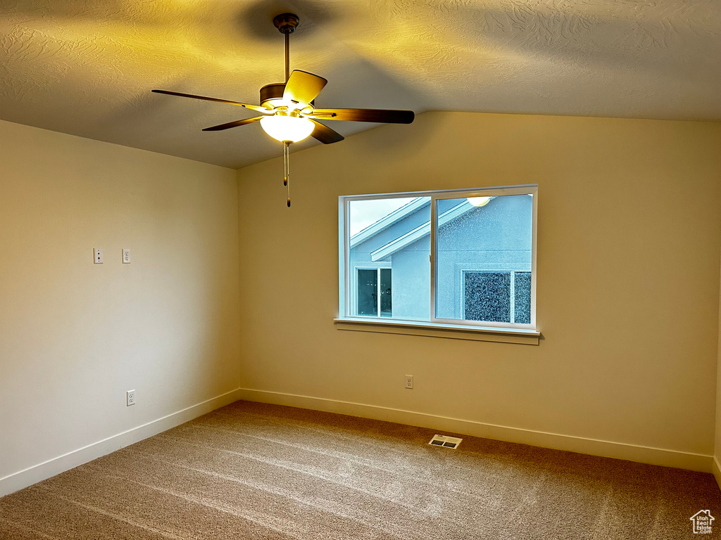Spare room featuring a textured ceiling, ceiling fan, carpet, and lofted ceiling