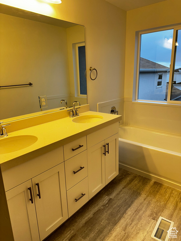 Bathroom featuring dual vanity, a bathtub, and wood-type flooring
