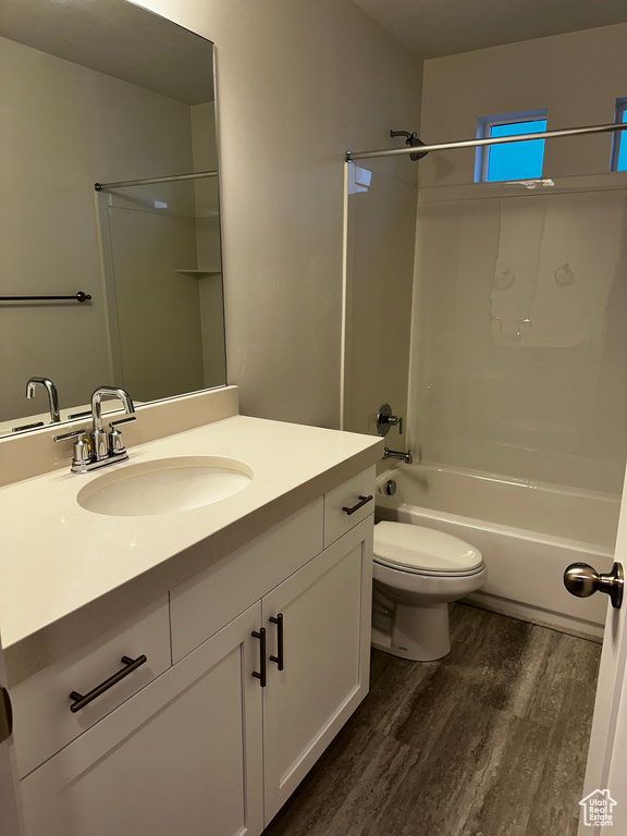 Full bathroom featuring hardwood / wood-style floors, washtub / shower combination, vanity, and toilet