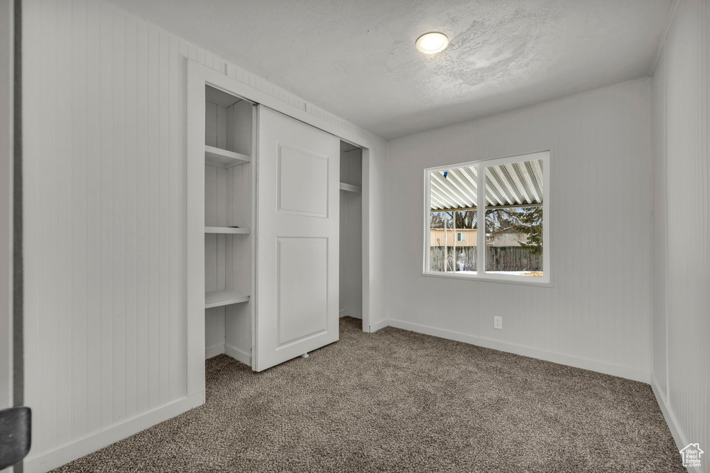 Unfurnished bedroom with a closet and dark colored carpet