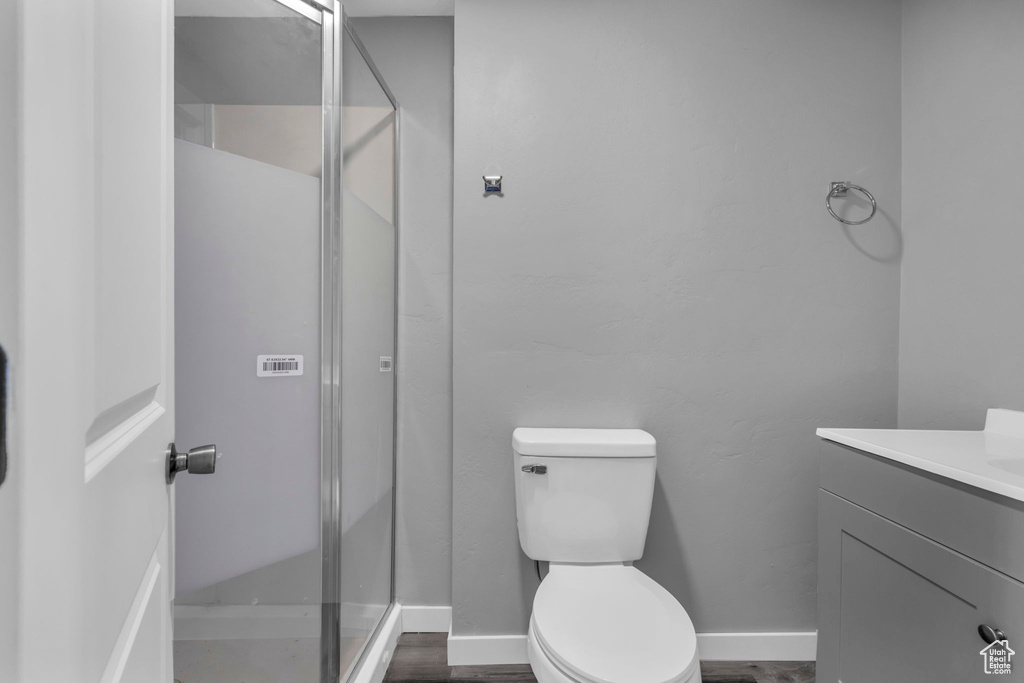 Bathroom featuring a shower with shower door, wood-type flooring, vanity, and toilet