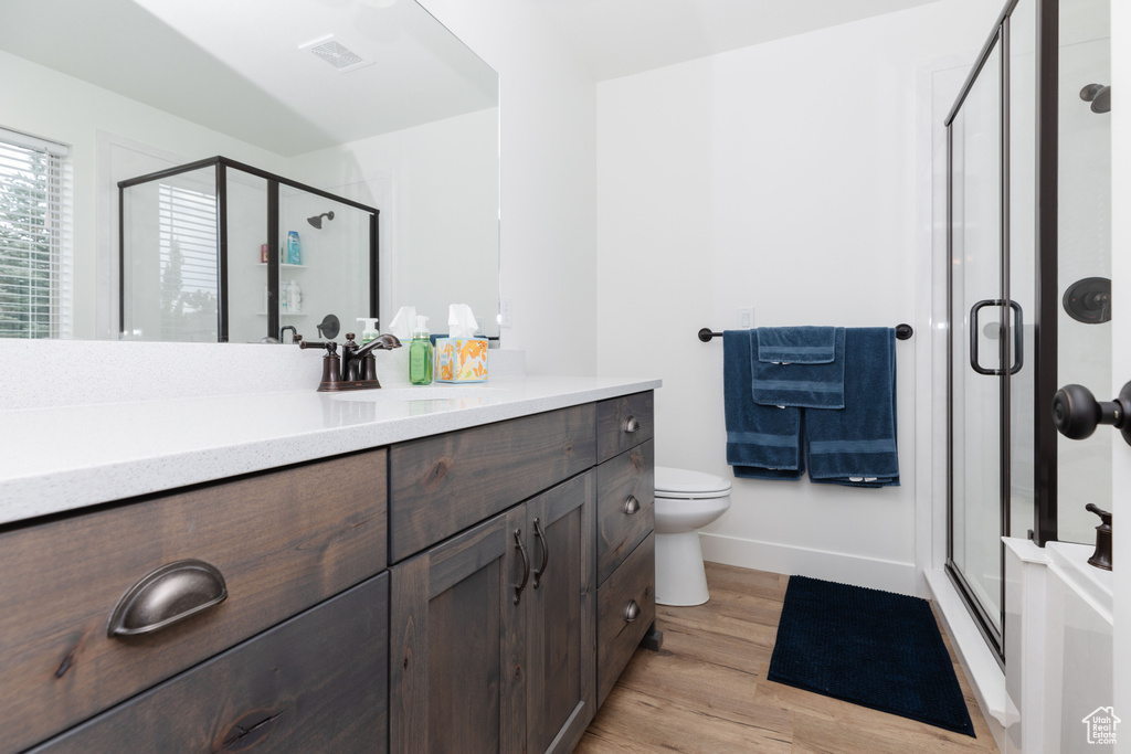 Bathroom with hardwood / wood-style floors, vanity, walk in shower, and toilet
