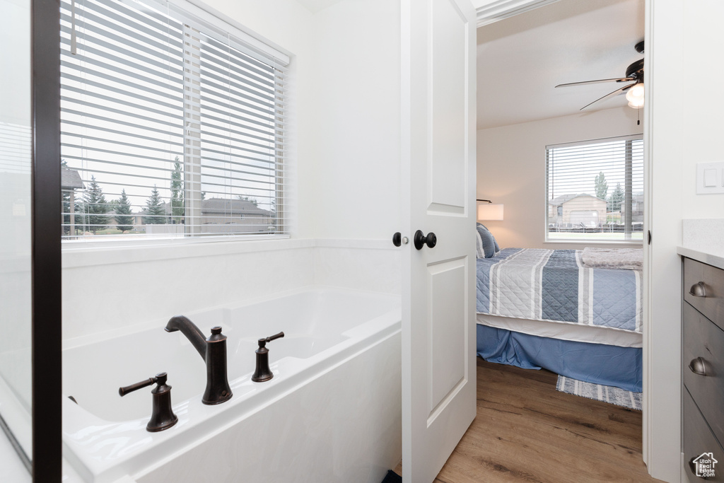 Bathroom with vanity, hardwood / wood-style floors, ceiling fan, and a tub