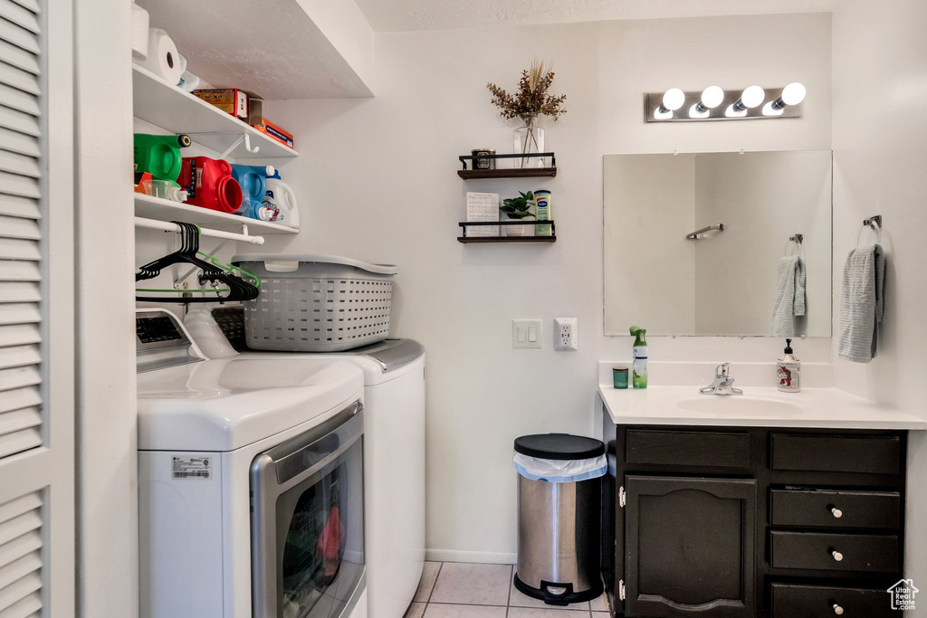 Laundry room featuring light tile flooring, sink, and washer and clothes dryer