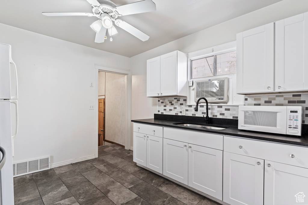 Kitchen featuring white cabinets, tasteful backsplash, white appliances, sink, and ceiling fan