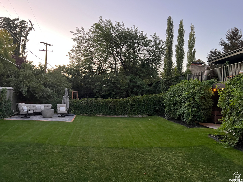 Yard at dusk featuring a patio area and an outdoor hangout area