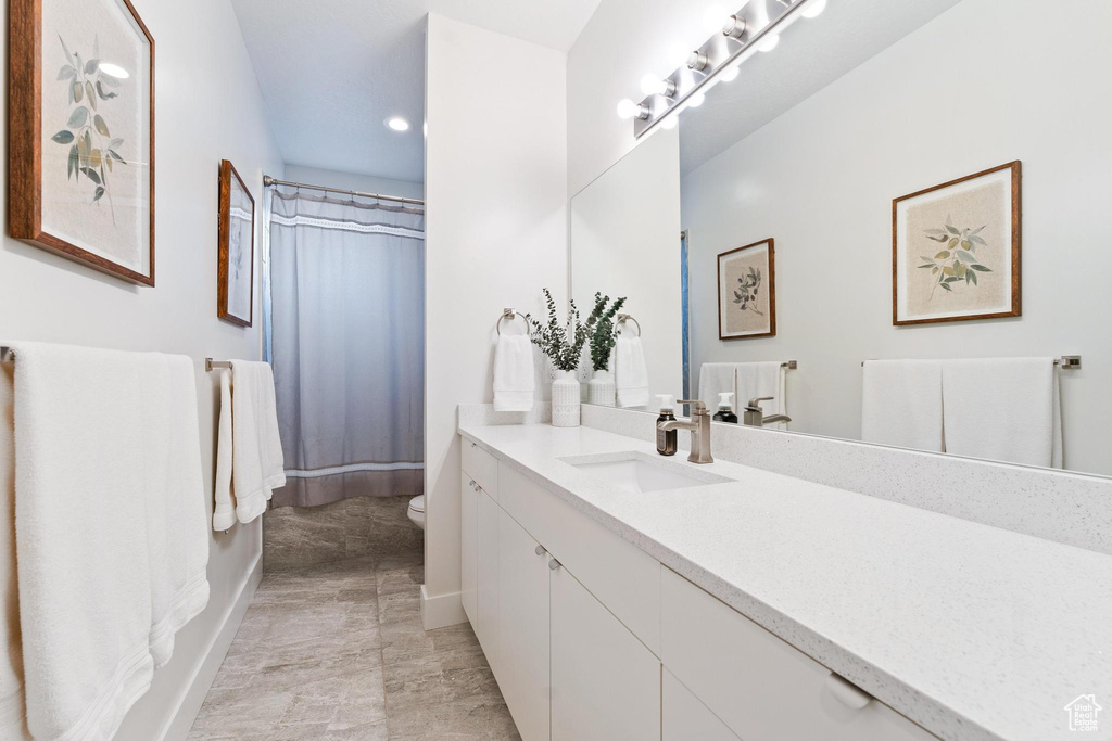 Bathroom featuring large vanity, tile floors, and toilet