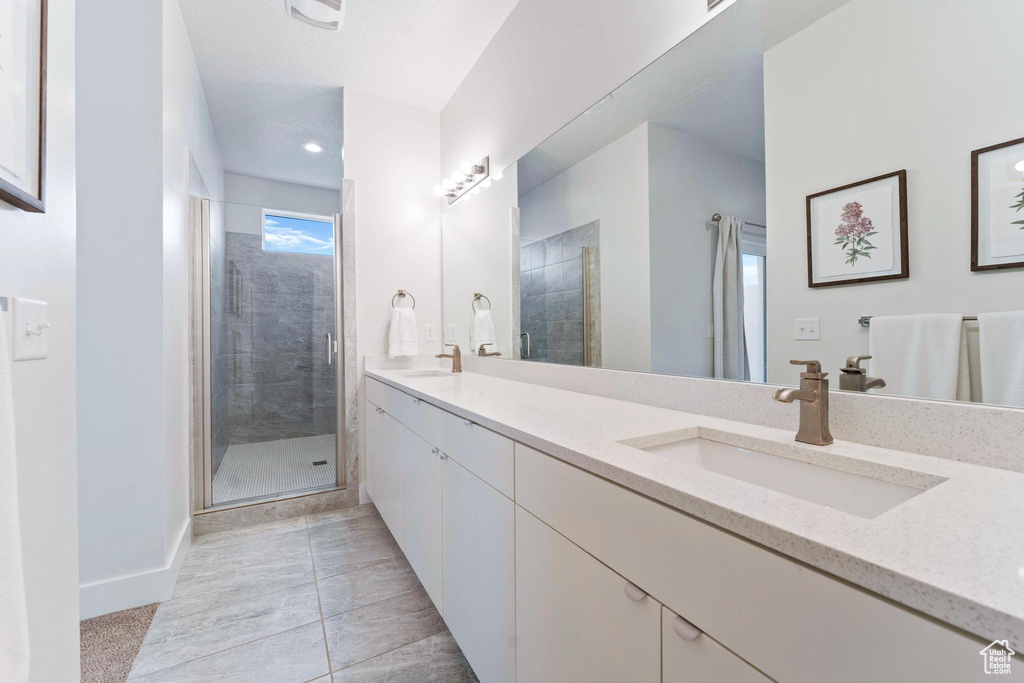 Bathroom featuring tile floors, double sink vanity, and walk in shower