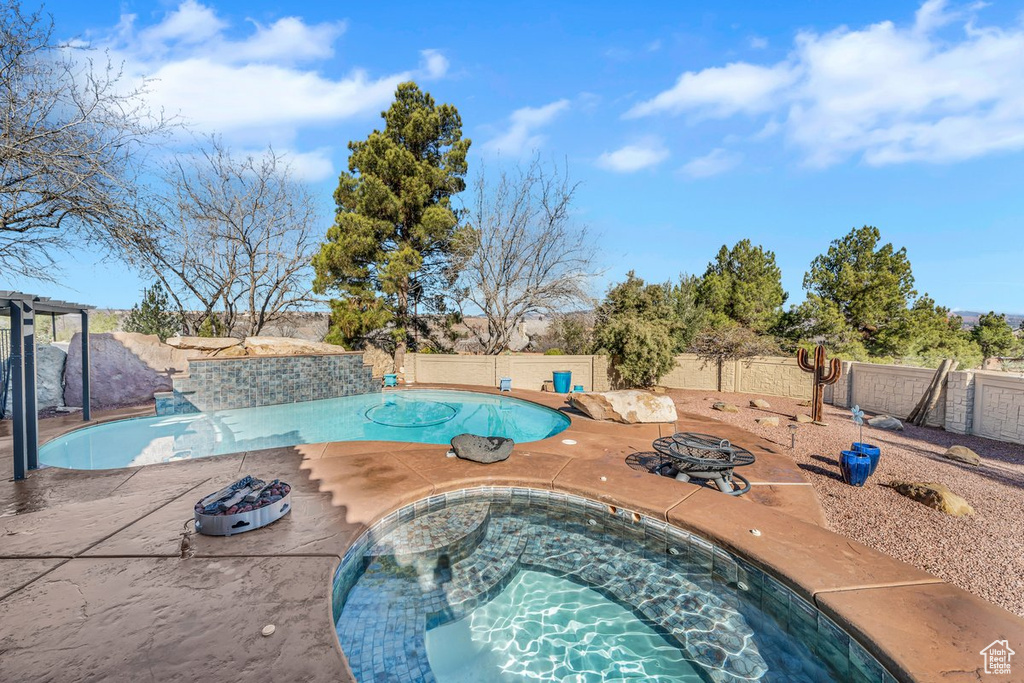 View of pool with a fire pit, an outdoor hot tub, a patio, and pool water feature
