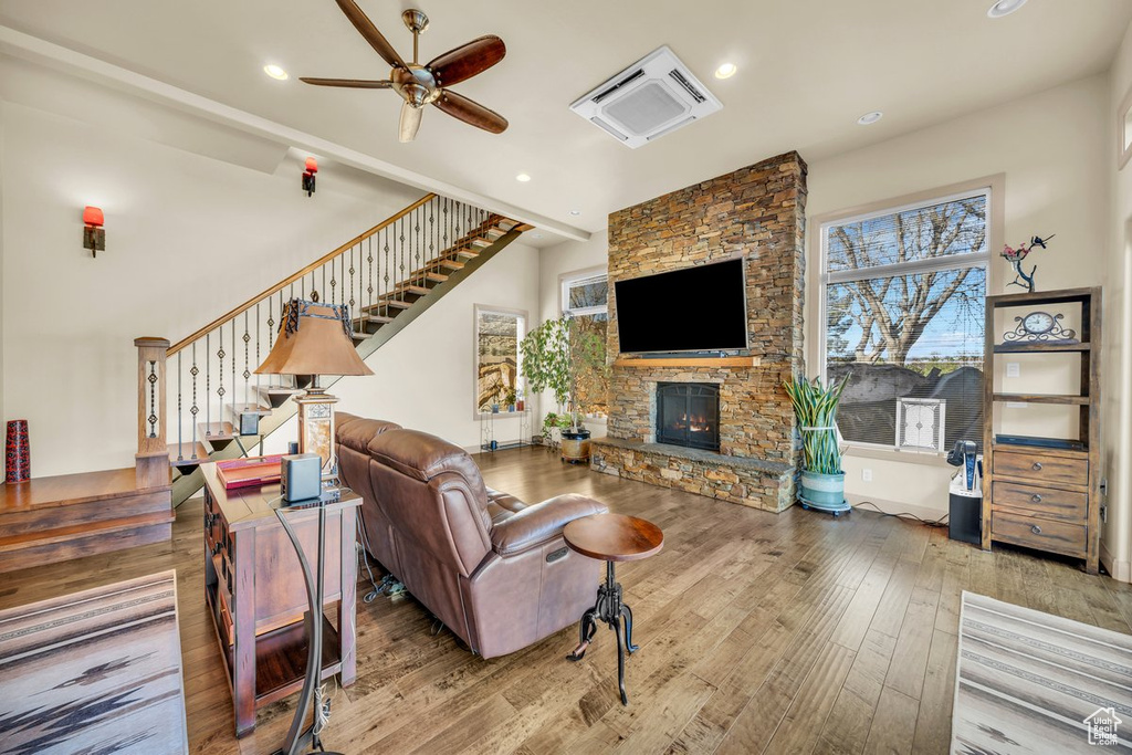Living room featuring a stone fireplace, ceiling fan, and hardwood / wood-style floors