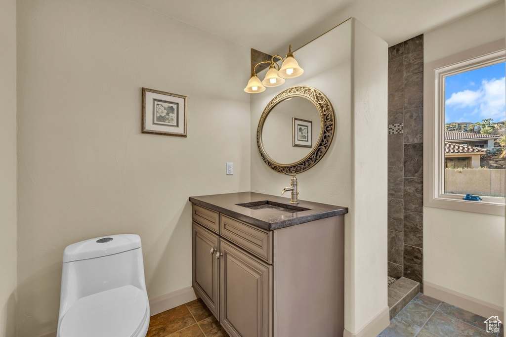 Bathroom featuring vanity, toilet, tiled shower, and tile flooring