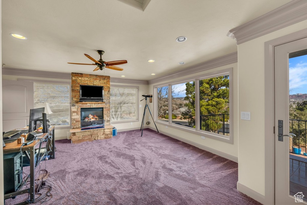 Carpeted living room featuring a fireplace, ceiling fan, and ornamental molding