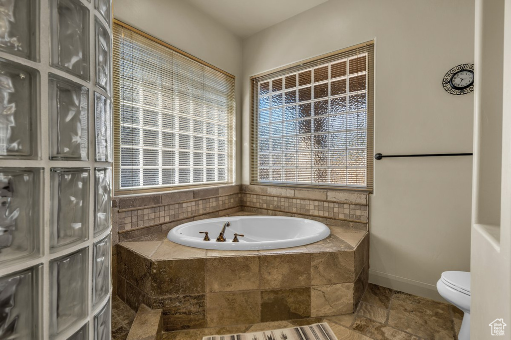 Bathroom with toilet, tile floors, and a relaxing tiled bath