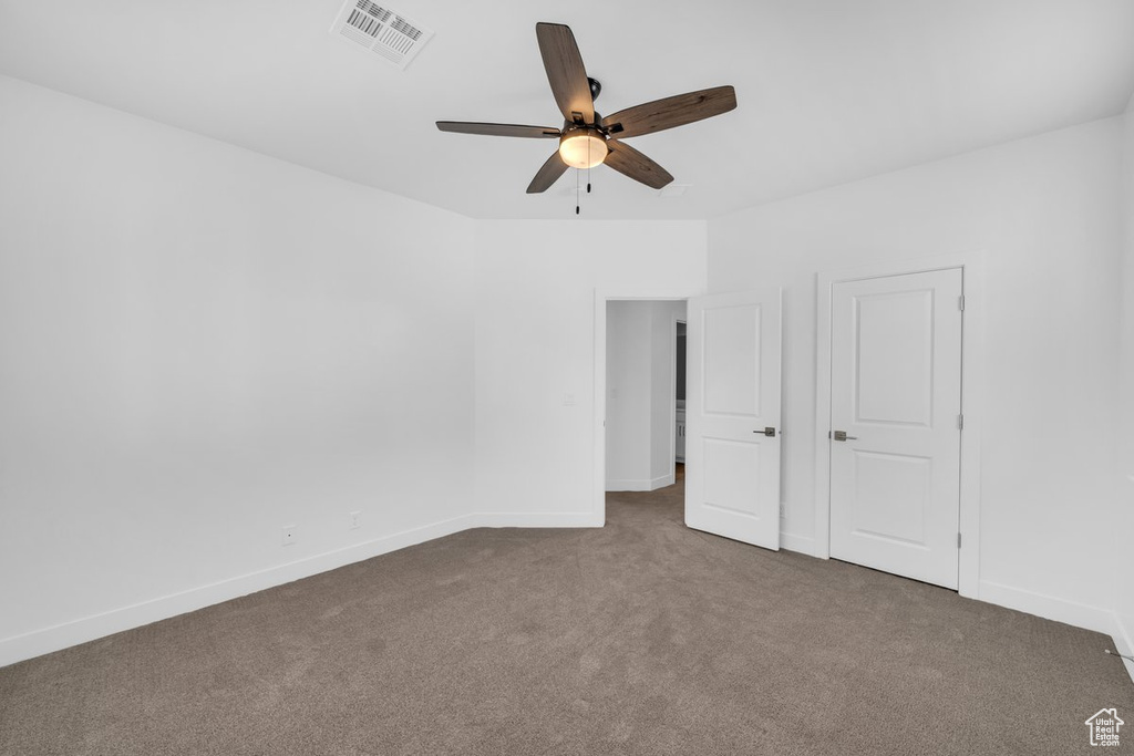 Unfurnished room featuring dark colored carpet and ceiling fan