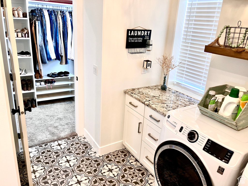 Laundry area featuring light tile flooring, washer / dryer, and cabinets
