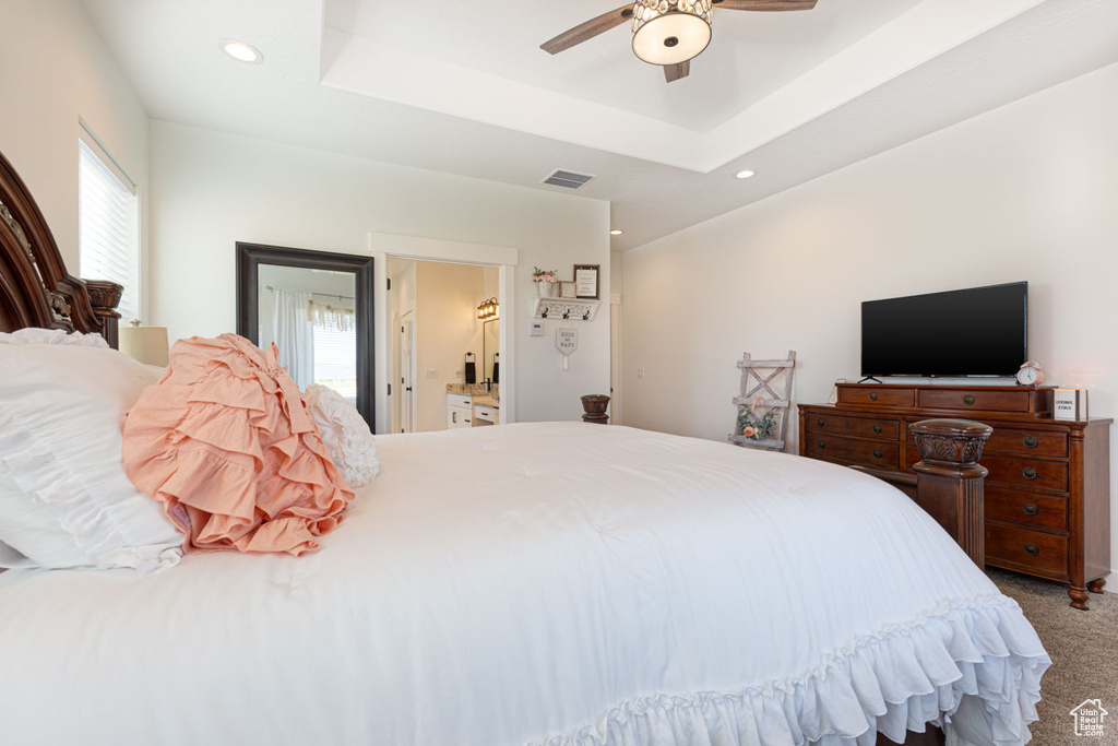 Bedroom featuring multiple windows, carpet floors, ceiling fan, and a tray ceiling