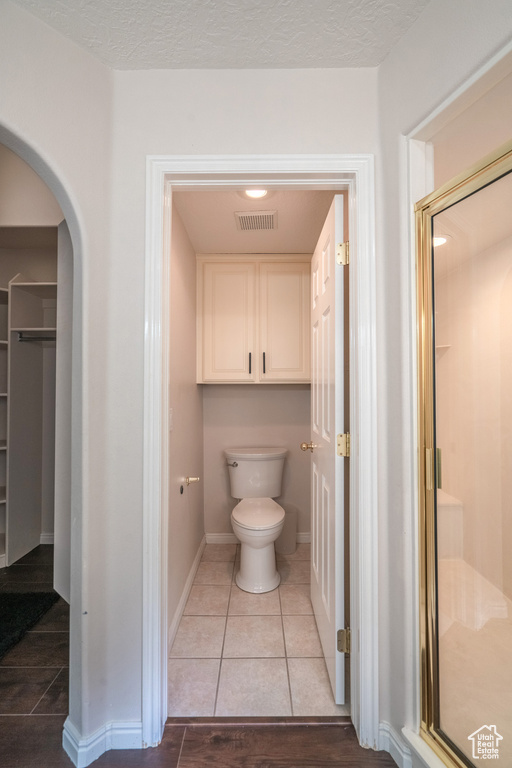 Bathroom featuring toilet, walk in shower, and tile flooring